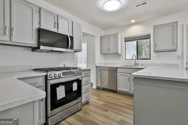 205 Shadowood Ln, Peachtree City, GA 30269 - kitchen with stainless steel appliances, gray cabinetry, light wood-type flooring, recessed lighting, and light stone counters