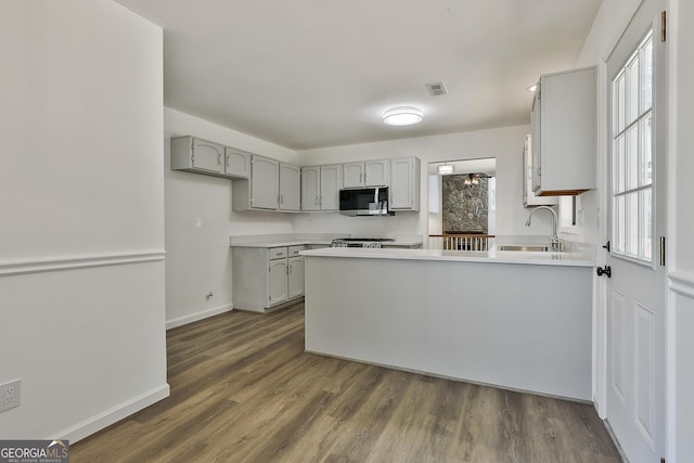 205 Shadowood Ln, Peachtree City, GA 30269 - kitchen with stainless steel microwave, a peninsula, gray cabinetry, dark wood-style flooring, and light countertops