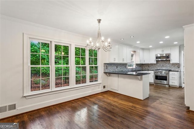 750 Crest Valley Dr NW, Sandy Springs, GA 30327 - kitchen featuring appliances with stainless steel finishes, a peninsula, a chandelier, dark wood finished floors, and dark countertops
