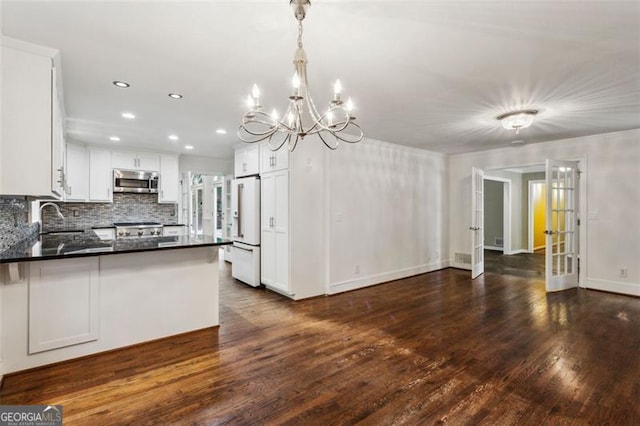 750 Crest Valley Dr NW, Sandy Springs, GA 30327 - kitchen with freestanding refrigerator, stainless steel microwave, dark wood-style flooring, a peninsula, and recessed lighting