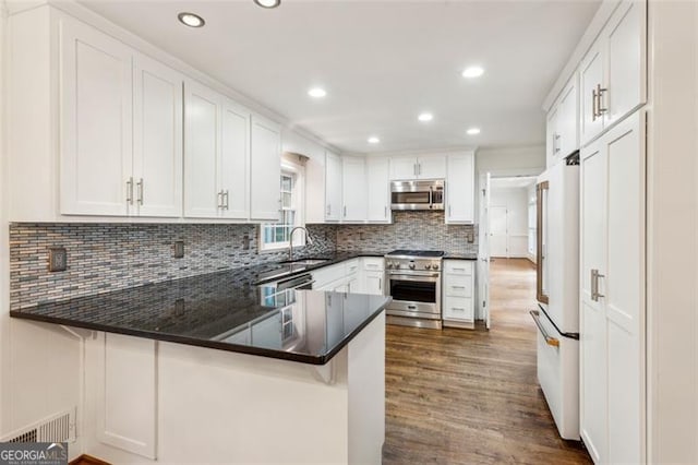 750 Crest Valley Dr NW, Sandy Springs, GA 30327 - kitchen featuring high quality appliances, white cabinets, dark wood finished floors, a peninsula, and recessed lighting