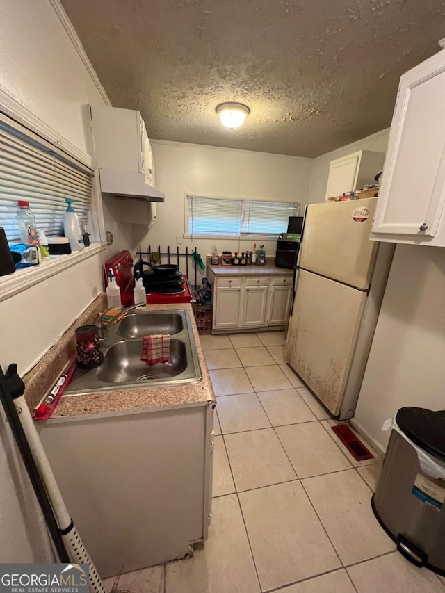 1750 Beechwood Blvd SW, Atlanta, GA 30311 - kitchen featuring freestanding refrigerator, under cabinet range hood, white cabinetry, light tile patterned floors, and a textured ceiling