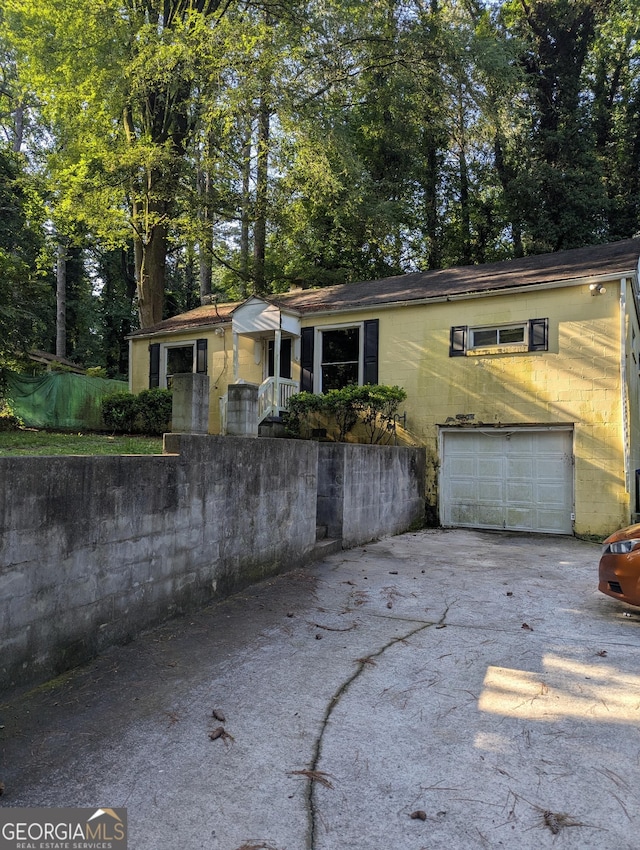 1750 Beechwood Blvd SW, Atlanta, GA 30311 - view of front facade featuring driveway, an attached garage, concrete block siding, and view of scattered trees