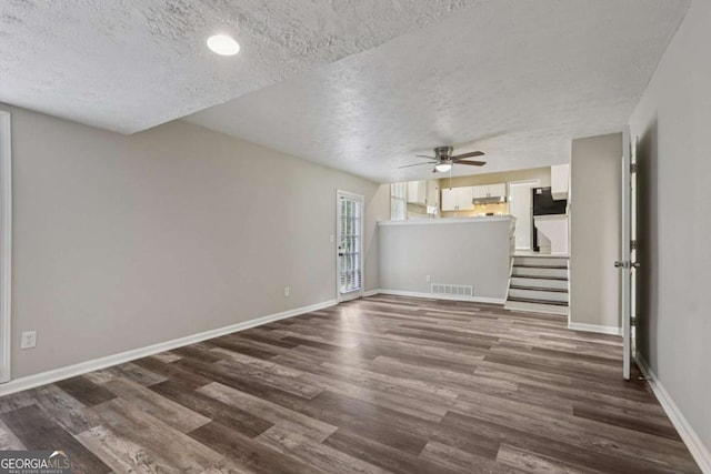 2849 Snapfinger Rd, Decatur, GA 30034 - unfurnished living room with a textured ceiling, dark wood-style flooring, ceiling fan, and stairway