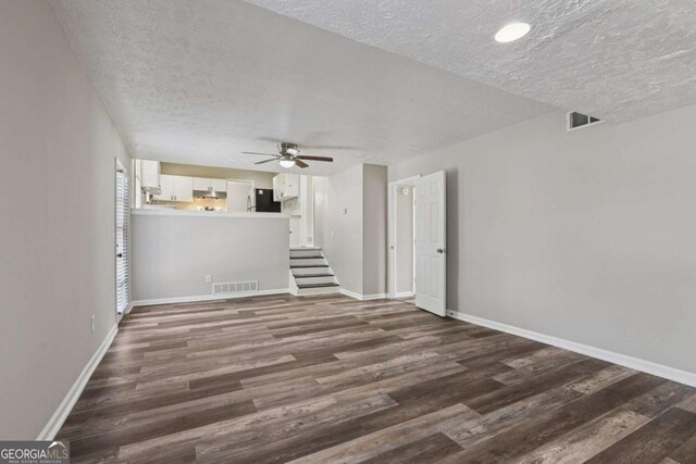 2849 Snapfinger Rd, Decatur, GA 30034 - unfurnished living room featuring a textured ceiling, a ceiling fan, dark wood-type flooring, and stairs