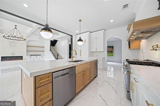 103 Maddox Rd, Buford, GA 30518 - kitchen featuring stainless steel appliances, exhaust hood, light marble finish floors, arched walkways, and light stone countertops