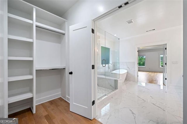 103 Maddox Rd, Buford, GA 30518 - bathroom featuring a shower stall, a freestanding bath, a walk in closet, and wood finished floors