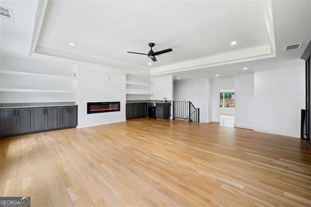 103 Maddox Rd, Buford, GA 30518 - unfurnished living room with a tray ceiling, ceiling fan, light wood-type flooring, a glass covered fireplace, and recessed lighting
