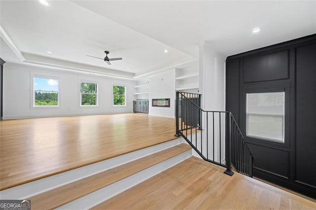 103 Maddox Rd, Buford, GA 30518 - unfurnished living room with light wood-type flooring, a ceiling fan, a glass covered fireplace, recessed lighting, and a raised ceiling
