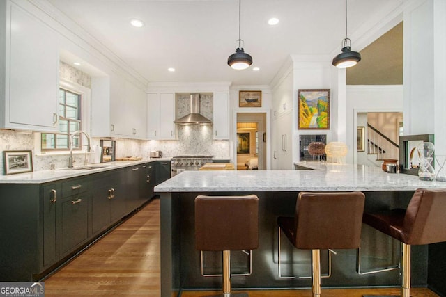 1833 N Rock Springs Rd NE, Atlanta, GA 30324 - kitchen with wall chimney range hood, white cabinets, a kitchen breakfast bar, decorative backsplash, and crown molding
