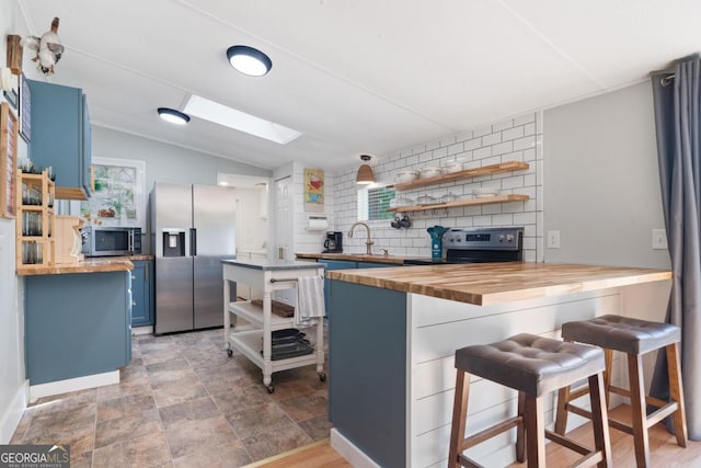 103 Fawn Ct, Eatonton, GA 31024 - kitchen featuring wood counters, stainless steel appliances, blue cabinets, open shelves, and a breakfast bar