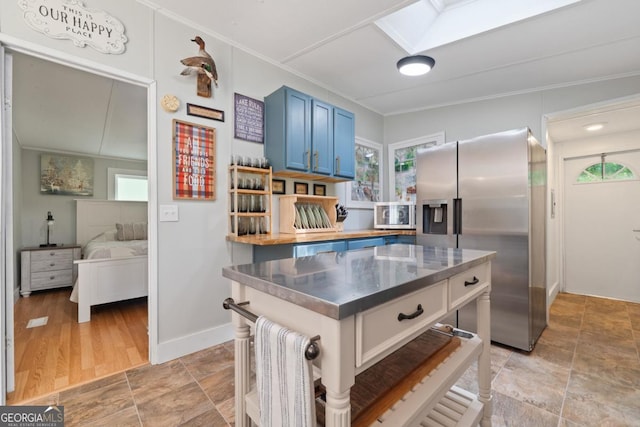 103 Fawn Ct, Eatonton, GA 31024 - kitchen with stainless steel appliances, blue cabinets, a skylight, healthy amount of natural light, and ornamental molding