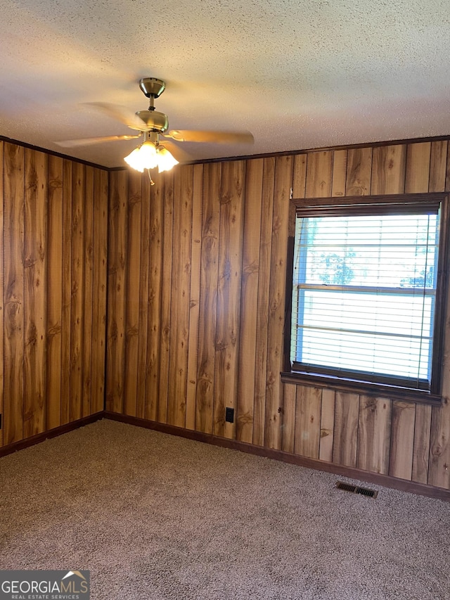 6617 18th St SW, Lanett, AL 36863 - unfurnished room with a textured ceiling, wooden walls, a ceiling fan, and carpet floors