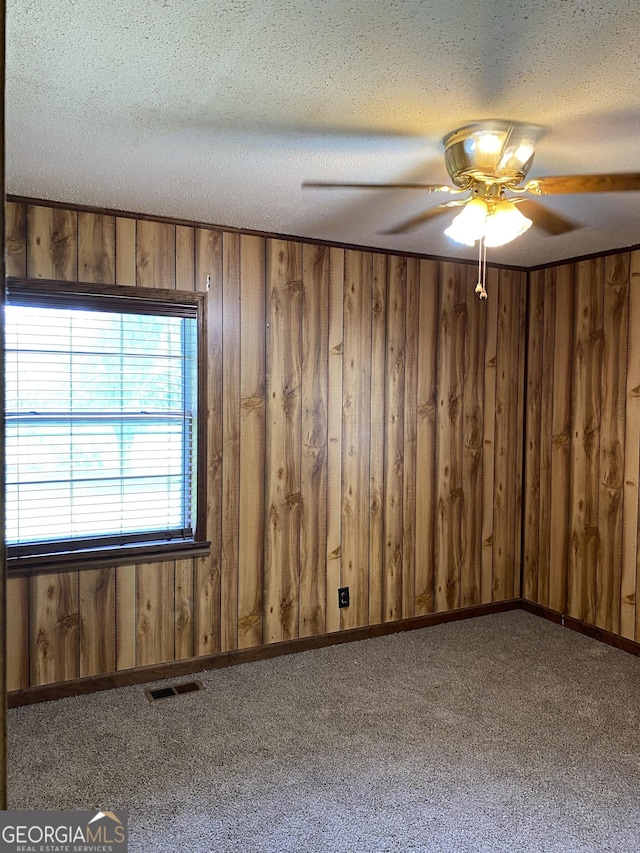 6617 18th St SW, Lanett, AL 36863 - empty room featuring a ceiling fan, wood walls, a textured ceiling, and carpet floors