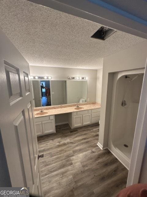 120 Foothill Dr, Dalton, GA 30720 - bathroom featuring wood finished floors, a textured ceiling, double vanity, and walk in shower