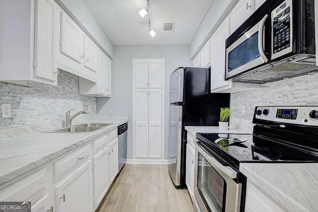 24317 Plantation Dr NE, Atlanta, GA 30324 - kitchen with stainless steel appliances, light wood-style flooring, white cabinets, decorative backsplash, and light stone countertops
