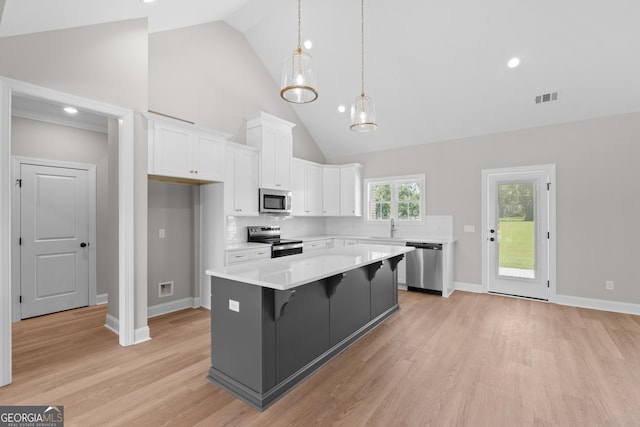 3 Honeysuckle Dr, Claxton, GA 30417 - kitchen with stainless steel appliances, white cabinetry, high vaulted ceiling, light wood-style flooring, and a kitchen island