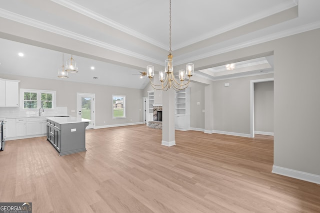 3 Honeysuckle Dr, Claxton, GA 30417 - unfurnished living room with a chandelier, light wood-style flooring, a brick fireplace, crown molding, and a raised ceiling