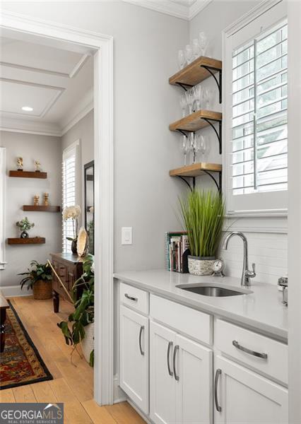 127 Oak Ln, Decatur, GA 30030 - bar featuring crown molding, light wood-style floors, and decorative backsplash