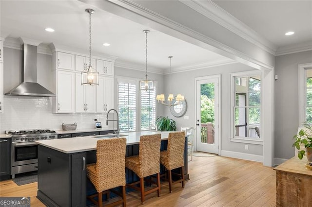 127 Oak Ln, Decatur, GA 30030 - kitchen featuring wall chimney range hood, high end range, light countertops, an island with sink, and decorative backsplash