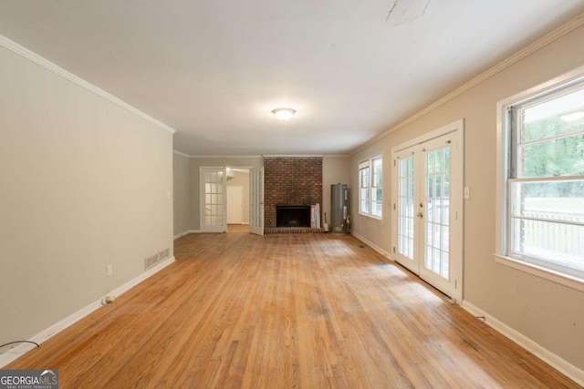 4201 Hicks Rd, Austell, GA 30106 - unfurnished living room with light wood-type flooring, a brick fireplace, crown molding, water heater, and french doors