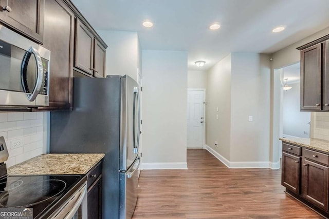2317 Church St, Hampton, GA 30228 - kitchen featuring appliances with stainless steel finishes, dark brown cabinets, wood finished floors, backsplash, and light stone countertops