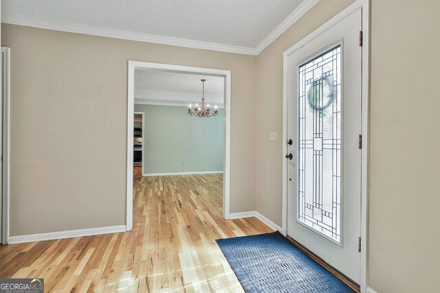 118 Whitfield Run, Peachtree City, GA 30269 - foyer entrance with a chandelier, light wood-style flooring, crown molding, and a textured ceiling