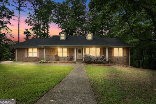 1290 Shadowlawn Dr NE, Conyers, GA 30012 - cape cod home featuring covered porch, brick siding, a yard, and roof with shingles