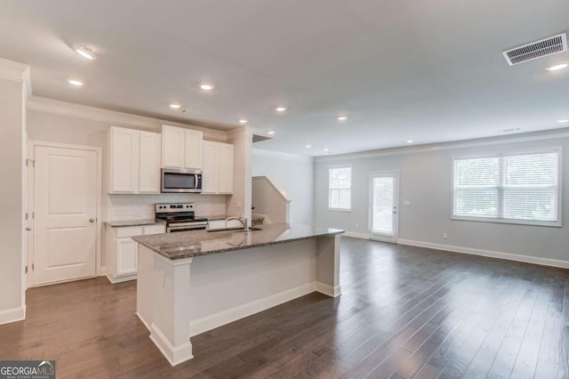 2005 Hamilton Creek Pkwy, Dacula, GA 30019 - kitchen with stainless steel appliances, dark stone counters, white cabinetry, decorative backsplash, and ornamental molding