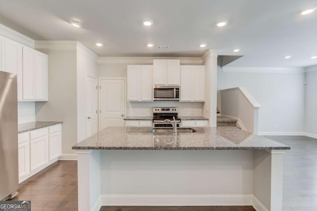 2005 Hamilton Creek Pkwy, Dacula, GA 30019 - kitchen featuring appliances with stainless steel finishes, stone countertops, ornamental molding, white cabinets, and dark wood-style floors