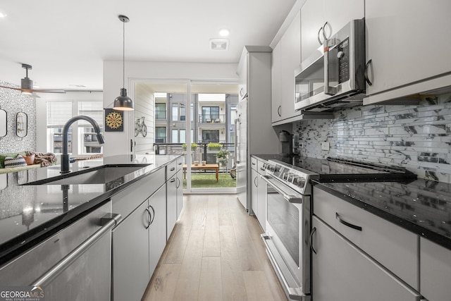 383 Pratt Dr Unit 506, Atlanta, GA 30315 - kitchen featuring appliances with stainless steel finishes, tasteful backsplash, dark stone counters, light wood-type flooring, and pendant lighting
