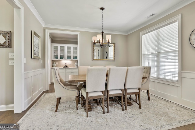 459 N Cove Dr, Newnan, GA 30263 - dining space with a chandelier, a decorative wall, ornamental molding, wood finished floors, and a wainscoted wall