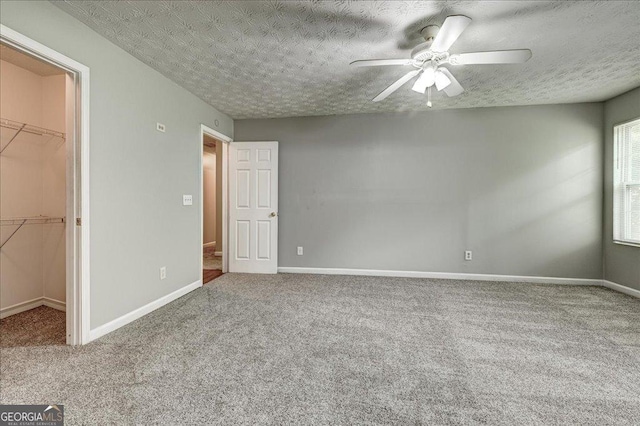 2898 Cedar Trace Dr, Ellenwood, GA 30294 - unfurnished bedroom with carpet, a spacious closet, a ceiling fan, and a textured ceiling
