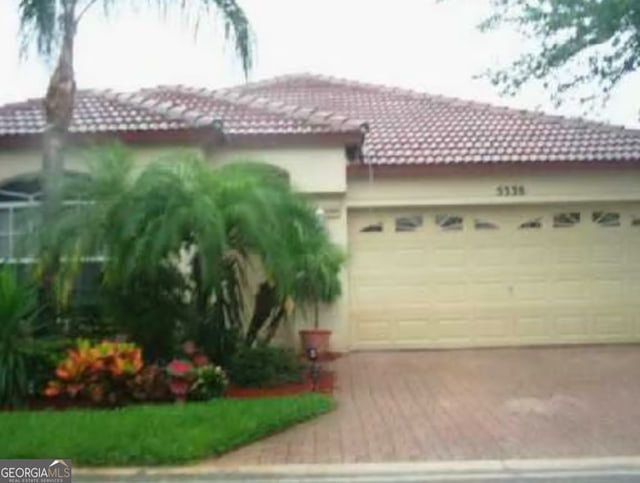 5338 Edenwood Ln, Riviera Beach, FL 33418 - view of front of house with a tiled roof, driveway, and an attached garage