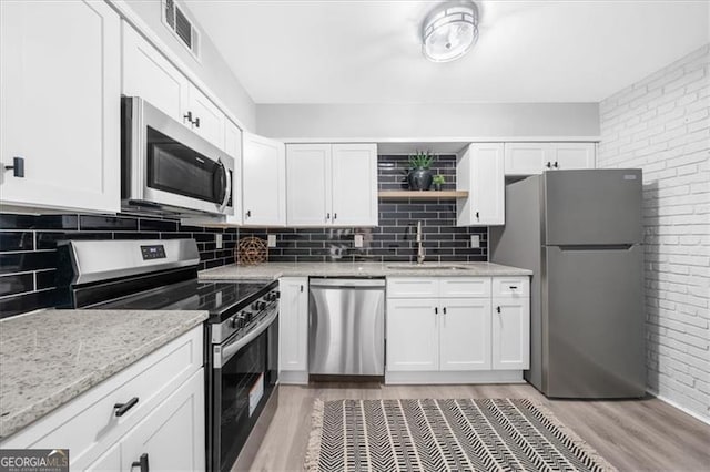 3091 Colonial Way Unit E4, Chamblee, GA 30341 - kitchen featuring stainless steel appliances, light wood finished floors, white cabinets, and brick wall