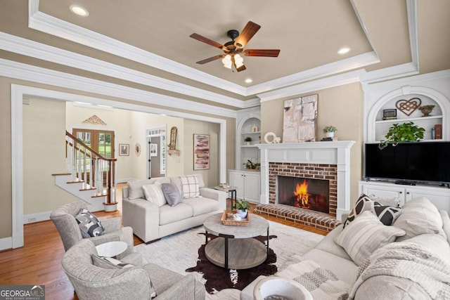 7615 Laurel Oak Dr, Suwanee, GA 30024 - living area featuring a raised ceiling, built in shelves, crown molding, ceiling fan, and a brick fireplace