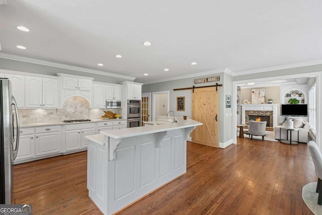 7615 Laurel Oak Dr, Suwanee, GA 30024 - kitchen featuring appliances with stainless steel finishes, ornamental molding, white cabinetry, a barn door, and a kitchen breakfast bar