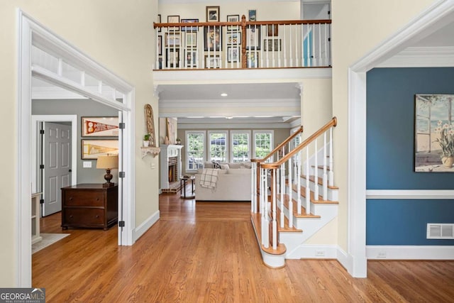 7615 Laurel Oak Dr, Suwanee, GA 30024 - foyer entrance featuring crown molding, wood finished floors, a fireplace, stairway, and a high ceiling