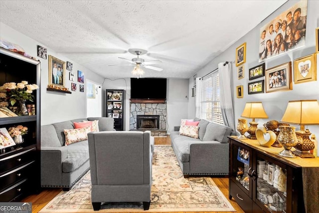 916 Marshall Fuller Rd, Dallas, GA 30157 - living area with wood finished floors, ceiling fan, a stone fireplace, and a textured ceiling