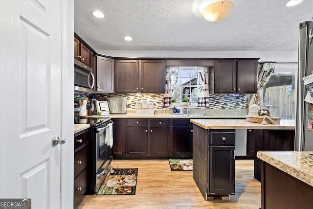 916 Marshall Fuller Rd, Dallas, GA 30157 - kitchen with stainless steel appliances, a textured ceiling, dark brown cabinets, light wood-type flooring, and backsplash