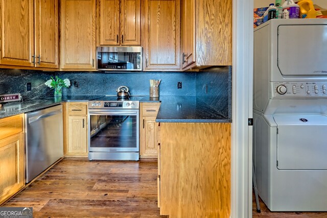 63 Maple Ridge Trl, Clayton, GA 30525 - kitchen featuring stainless steel appliances, stacked washer / drying machine, backsplash, wood finished floors, and dark stone countertops