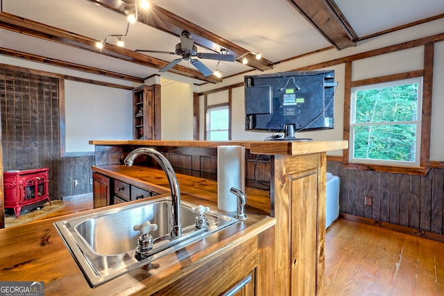 63 Maple Ridge Trl, Clayton, GA 30525 - kitchen featuring a wood stove, wooden walls, beam ceiling, ceiling fan, and light wood finished floors