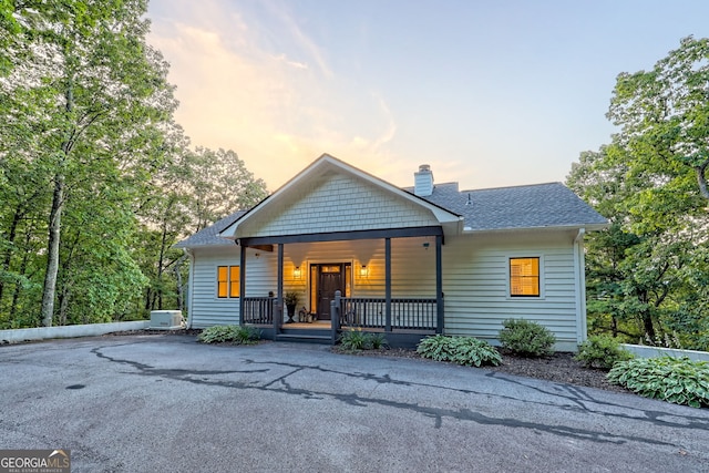 63 Maple Ridge Trl, Clayton, GA 30525 - view of front facade featuring covered porch, a chimney, and roof with shingles
