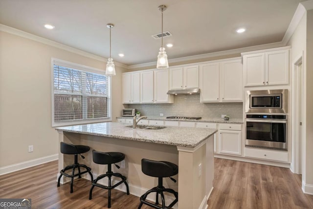 4636 SW Silver Oak Dr SW, Gainesville, GA 30504 - kitchen featuring appliances with stainless steel finishes, under cabinet range hood, crown molding, backsplash, and white cabinets