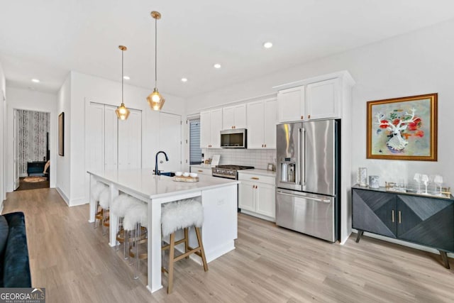 103 Marina Parc Dr, Waleska, GA 30183 - kitchen featuring stainless steel appliances, light wood finished floors, white cabinets, tasteful backsplash, and a breakfast bar area