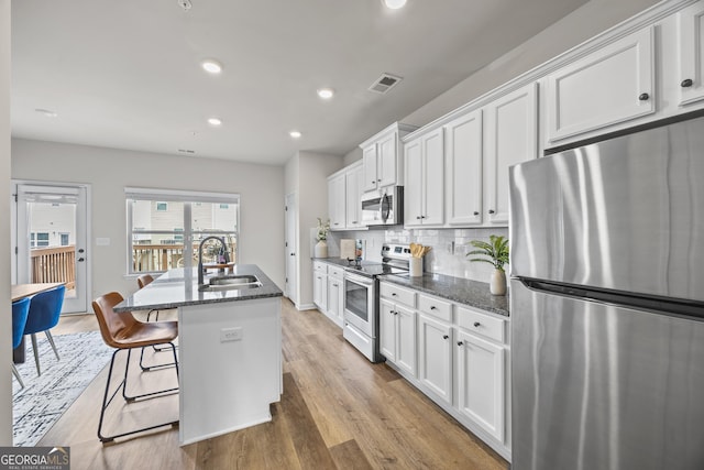 1004 Bayrose Cir, East Point, GA 30344 - kitchen with appliances with stainless steel finishes, white cabinetry, an island with sink, recessed lighting, and light wood-style floors