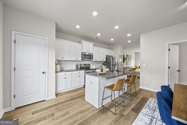 1004 Bayrose Cir, East Point, GA 30344 - kitchen featuring appliances with stainless steel finishes, a kitchen island with sink, a breakfast bar, white cabinetry, and recessed lighting