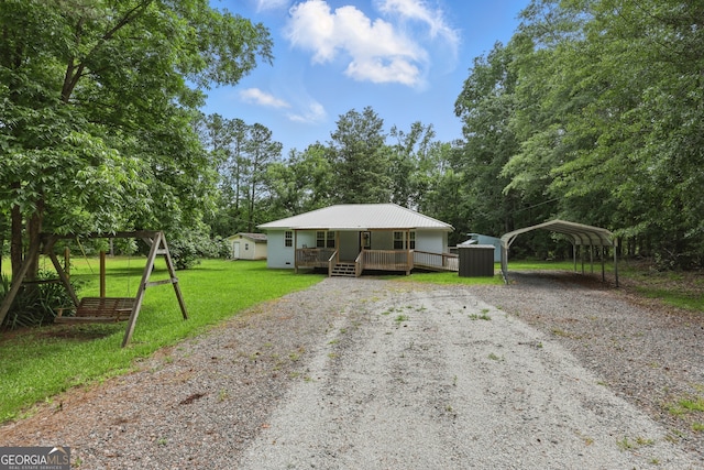 1469 Tabernacle Church Rd, Lincolnton, GA 30817 - view of front of home with covered porch, gravel driveway, a carport, a front lawn, and a metal roof