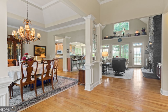 281 Hightower Lake Trl, Ball Ground, GA 30107 - dining area with a towering ceiling, ornate columns, light wood-style flooring, a chandelier, and a fireplace