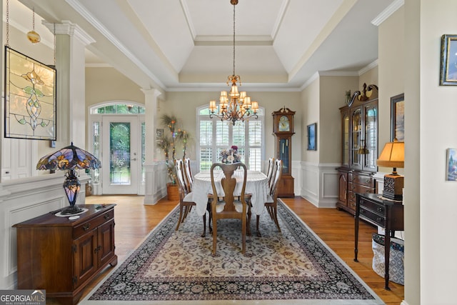 281 Hightower Lake Trl, Ball Ground, GA 30107 - dining space featuring a tray ceiling, a chandelier, wood finished floors, a wainscoted wall, and decorative columns